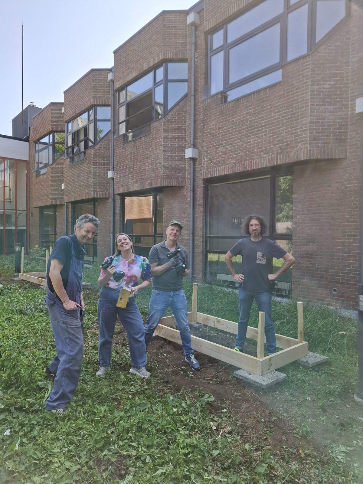 een workshopgever poseert met enkele collega's naast de basis van een plantenbak
